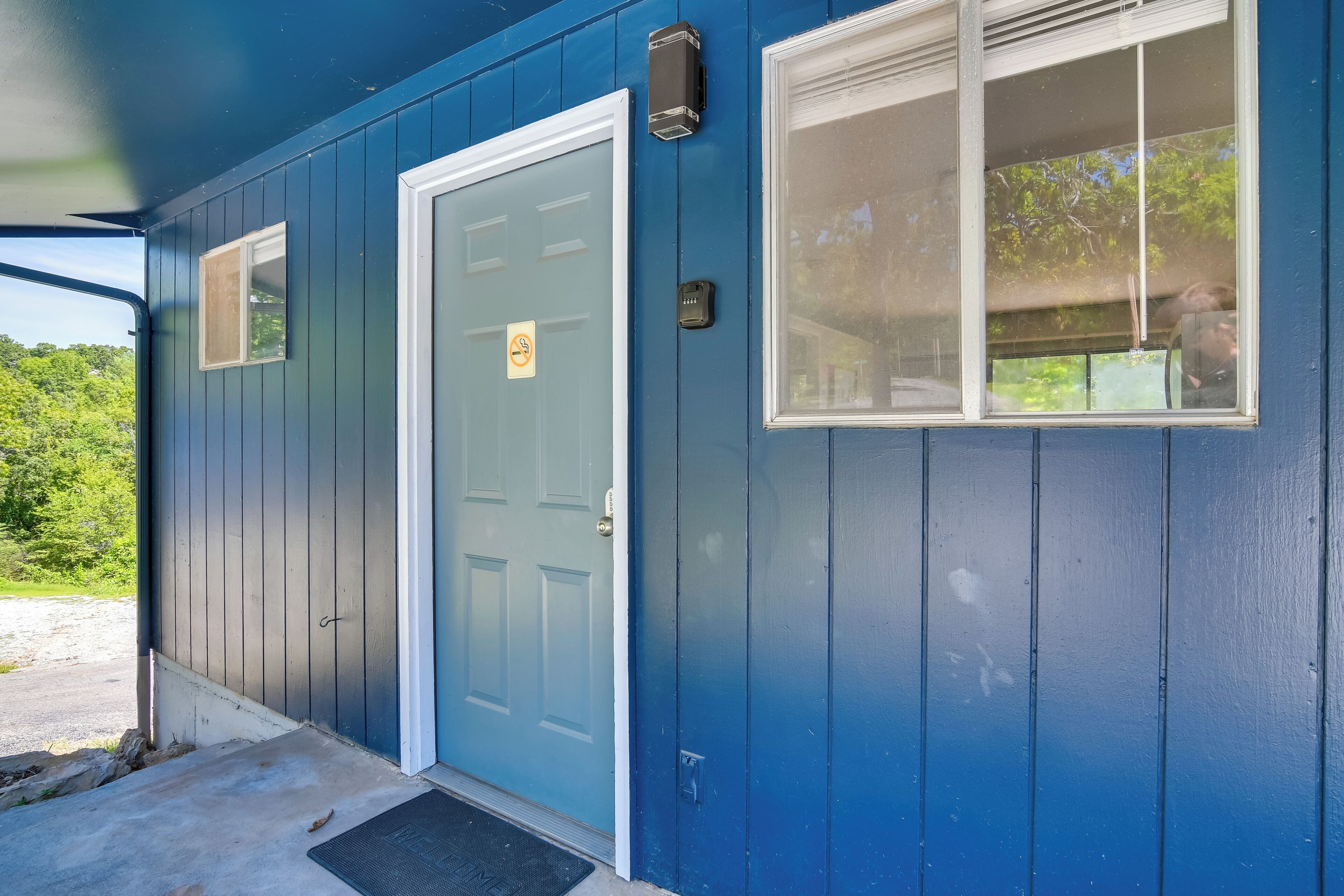 A blue building with a front door, a small window, and a doorbell.