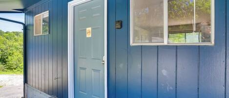 A blue building with a front door, a small window, and a doorbell.