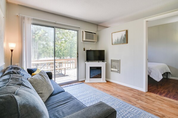 A modern living room with a sofa, a fireplace, a television, and a sliding glass door leading to an outdoor area. - Lakefront Haven: Boat Slip, Deck & Community Pool! (Kimberling City)