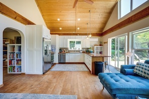 A spacious kitchen with wooden floors, white cabinets, and a large window.