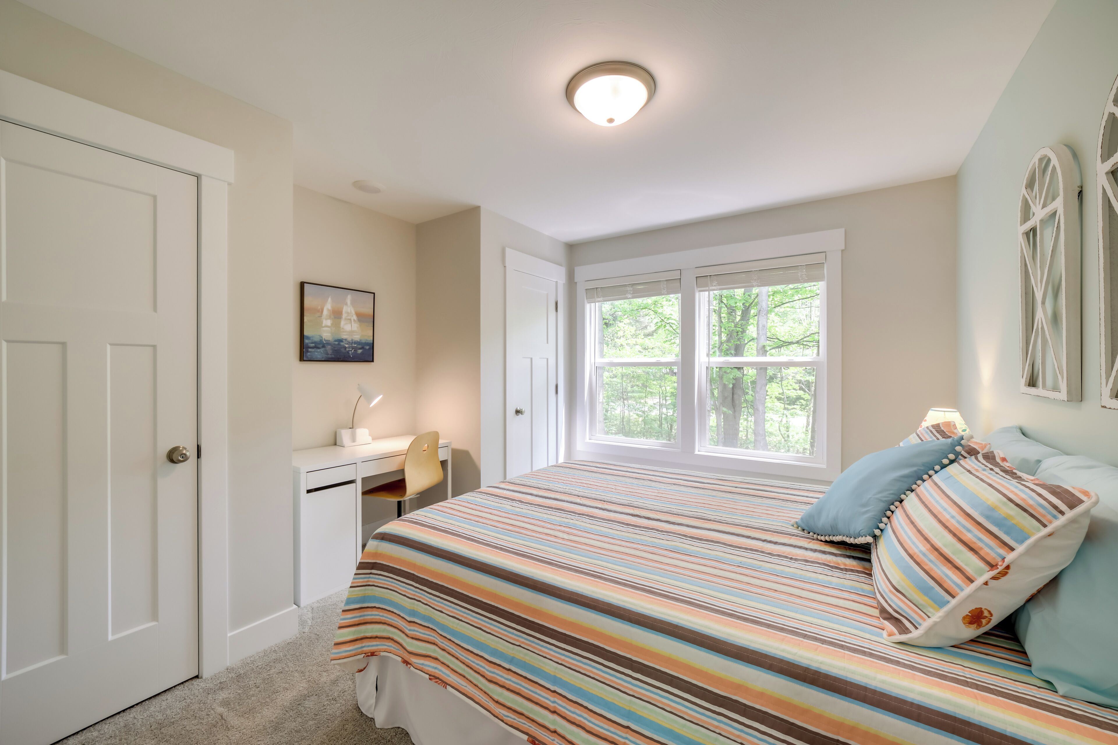 A bedroom with a bed, a desk, and a window.