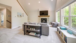 A spacious living room with a fireplace, a sofa, a coffee table, and a bookshelf. - Holland Home w/ Fire Pit: Walk to Lake Michigan! (Holland)