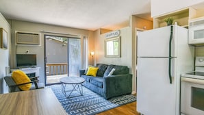 Ein gemütlicher Wohnbereich mit Sofa, Esstisch, Fernseher, Kühlschrank und Mikrowelle.