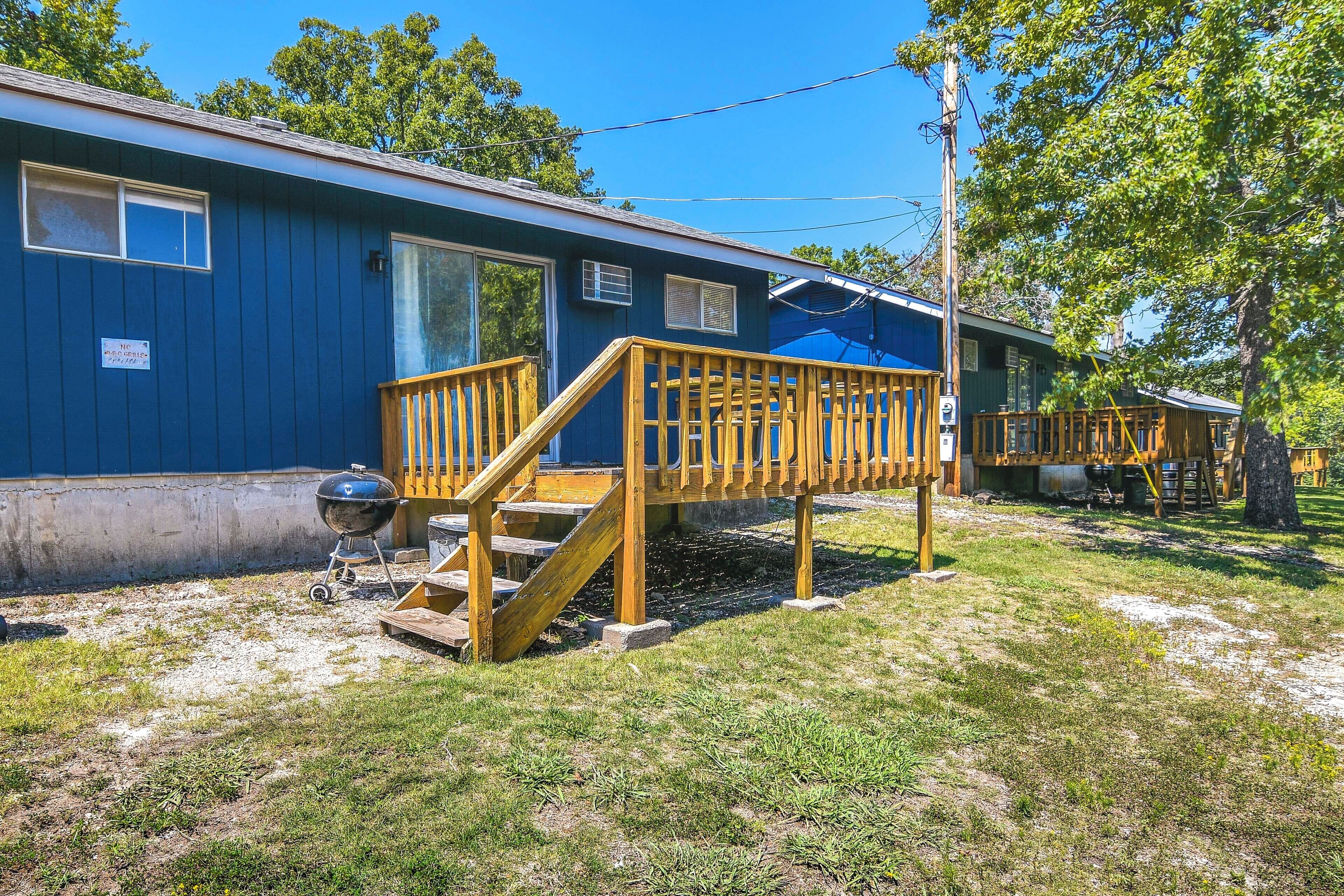 Una casa mobile blu con una veranda in legno e un barbecue.