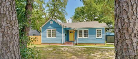 A single-story house with a blue exterior, a yellow front door, and a small porch.
