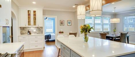 A modern kitchen with white cabinets, a large island, and pendant lighting.