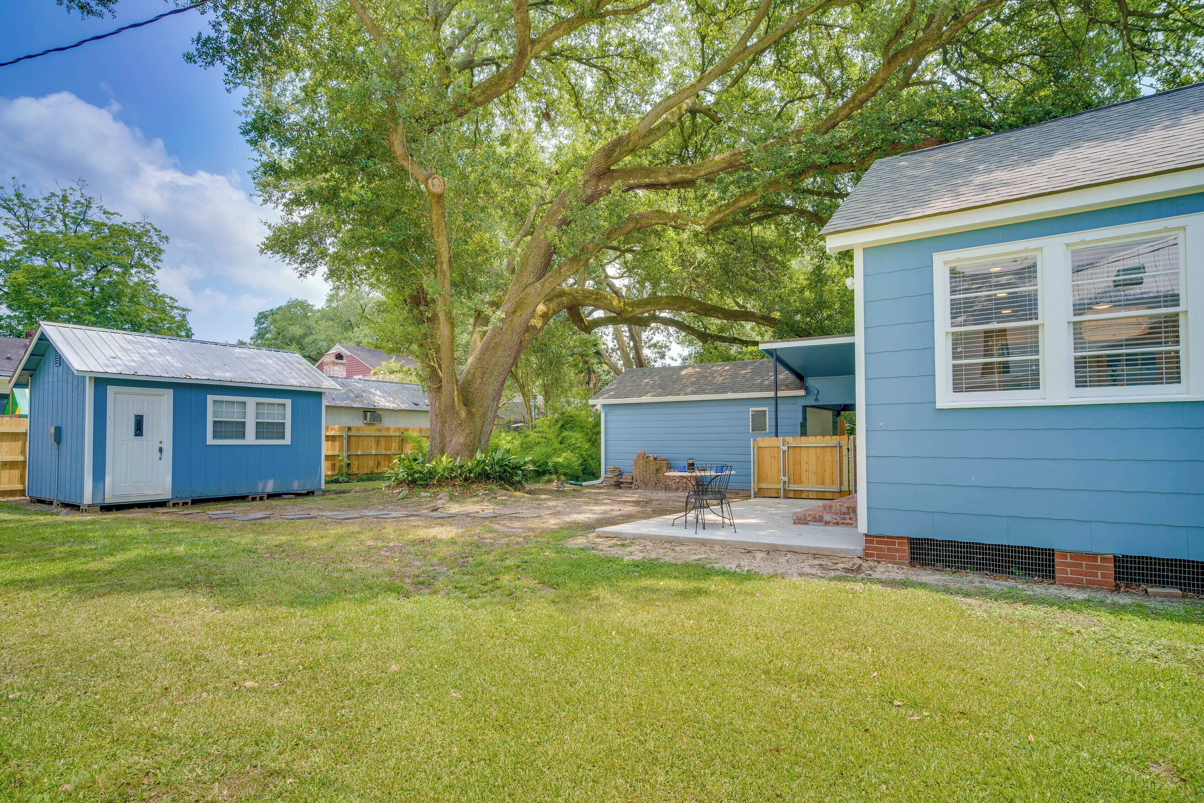 A residential area with two blue houses, a large tree, and a grassy yard.