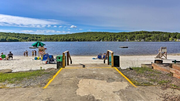 A beach with a concrete walkway leading to the water, surrounded by greenery and a clear sky. - Pools & Ski Access: Lackawaxen Cottage w/ Deck! (Lackawaxen)