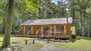 A rustic cabin with a wooden deck, surrounded by trees. - Pools & Ski Access: Lackawaxen Cottage w/ Deck! (Lackawaxen)