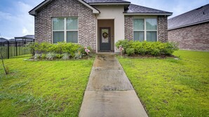 A two-story house with a brick facade, a front door, and a concrete pathway leading to the entrance. - Baton Rouge Vacation Rental: 5 Mi to Lsu! (Baton Rouge)