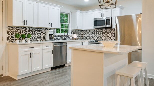 A modern kitchen with white cabinets, a stainless steel refrigerator, a microwave, and a dishwasher. - Charming Cary Home ~ 10 Mi to Downtown Raleigh! (Cary)