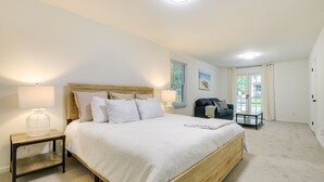 A bedroom with a large bed, bedside tables, a nightstand, a chair, and a window with curtains. - Charming Cary Home ~ 10 Mi to Downtown Raleigh! (Cary)