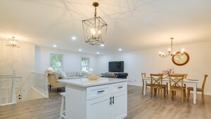 A spacious kitchen with a central island, white cabinetry, and a dining area with wooden chairs and a table. - Charming Cary Home ~ 10 Mi to Downtown Raleigh! (Cary)