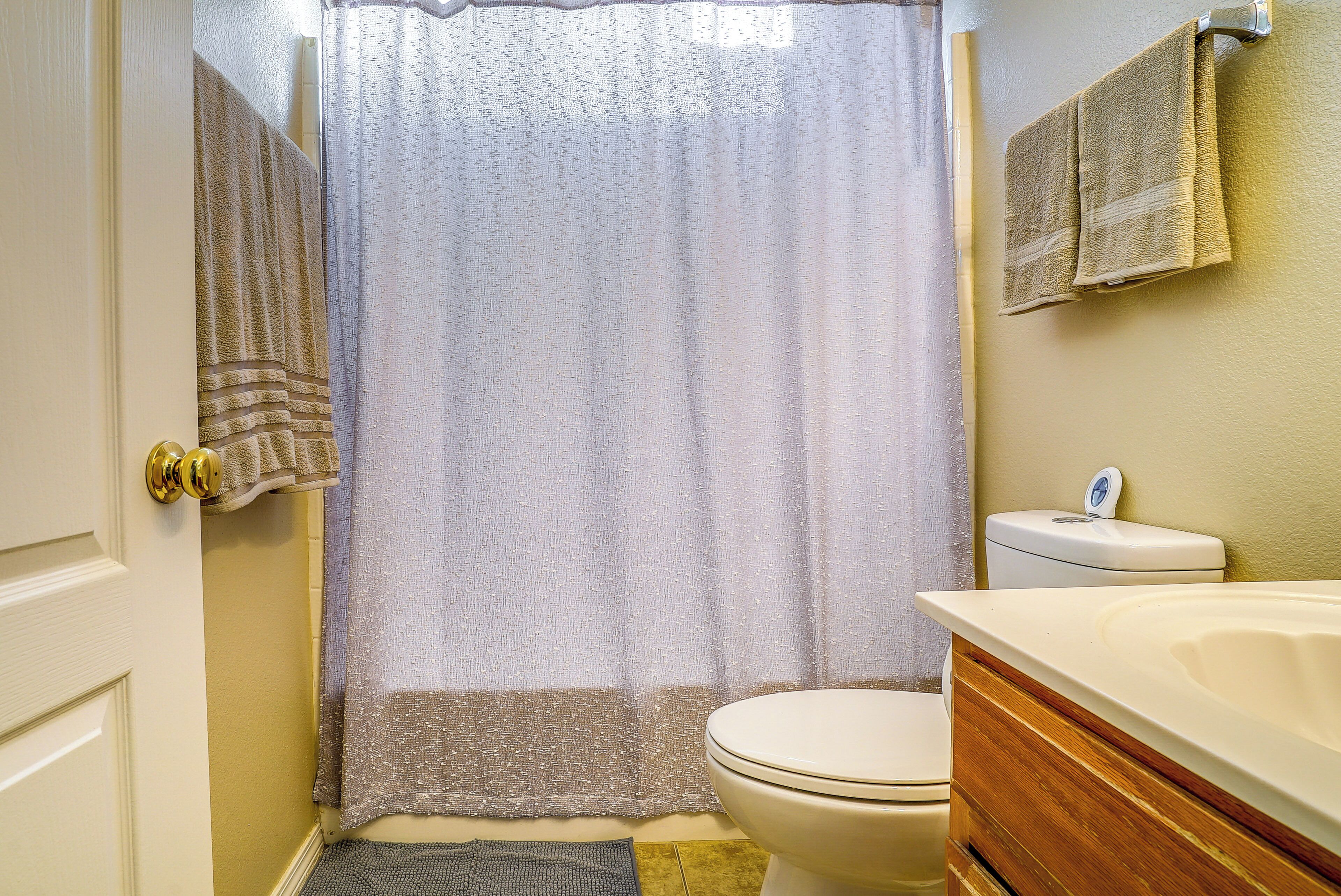 A bathroom with a toilet, a bathtub with a shower curtain, and a towel hanging on the wall.