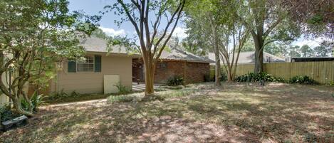 A residential property with a brick house, a wooden fence, and a well-maintained lawn.