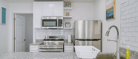 A modern kitchen with white cabinets, stainless steel appliances, granite countertops, and a sink with a modern faucet.
