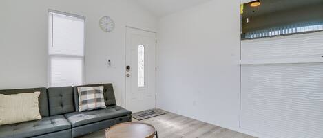 A modern living room with a black leather sofa, a wooden side table, and a white door with a glass window.