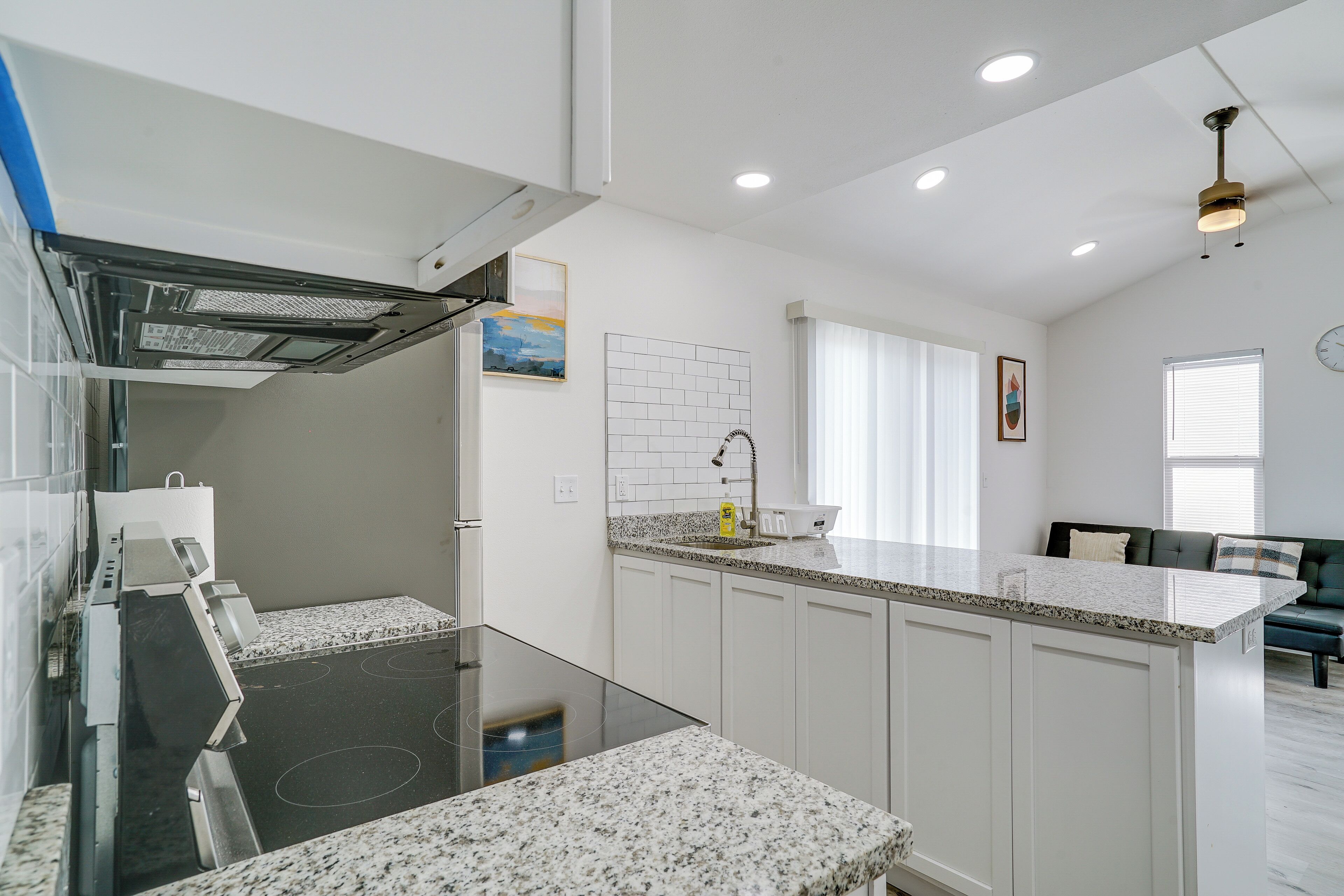 A modern kitchen with a central island, white cabinetry, and a built-in stove.