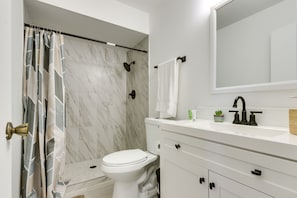 Un baño con ducha, inodoro, lavabo y espejo.
