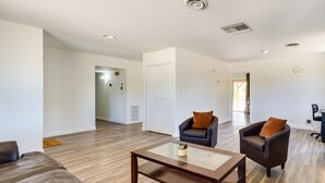 A spacious living room with a wooden floor, two leather armchairs, a glass coffee table, and a sofa. - Quiet Ridgecrest Vacation Rental w/ Private Yard! (Ridgecrest)