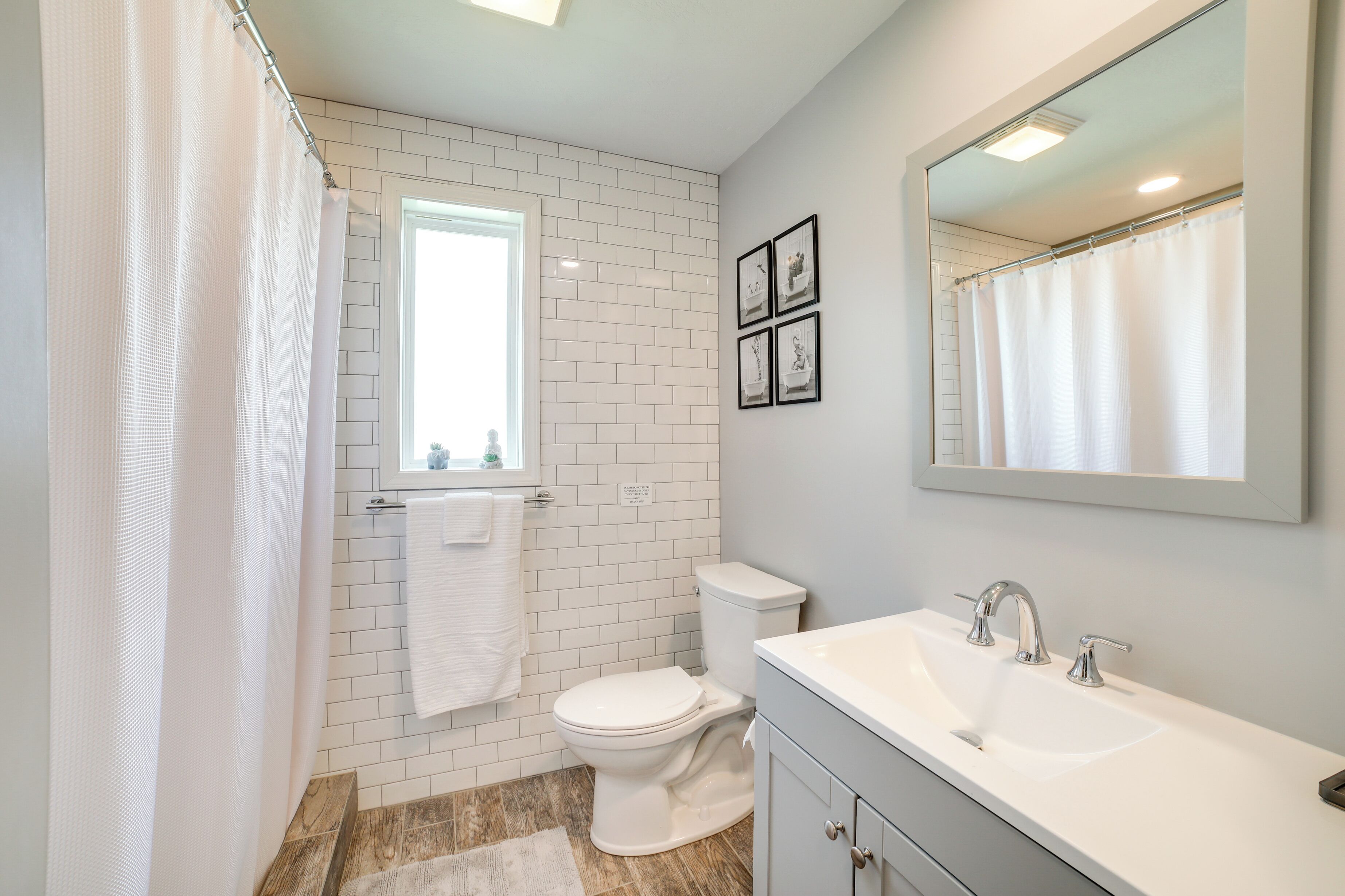 A bathroom with a white toilet, a sink with a mirror, and a shower curtain.