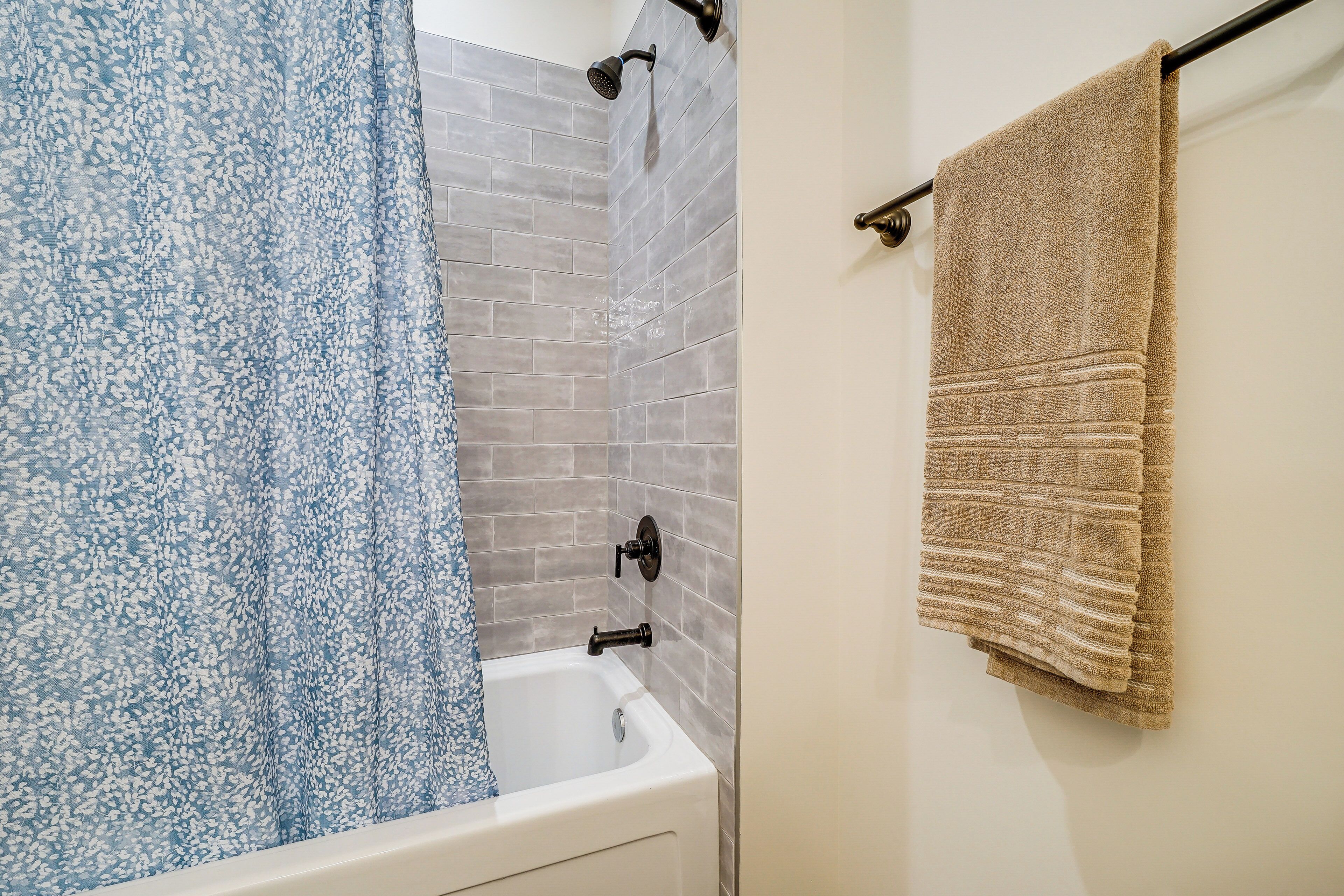 Un baño con ducha, bañera y un perchero para toallas.