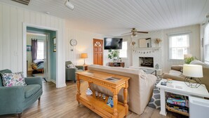 A living room with a wooden coffee table, a sofa, a TV, and a fireplace. - Carolina Beach Home w/ Private Deck: Walk to Shore (Carolina Beach)