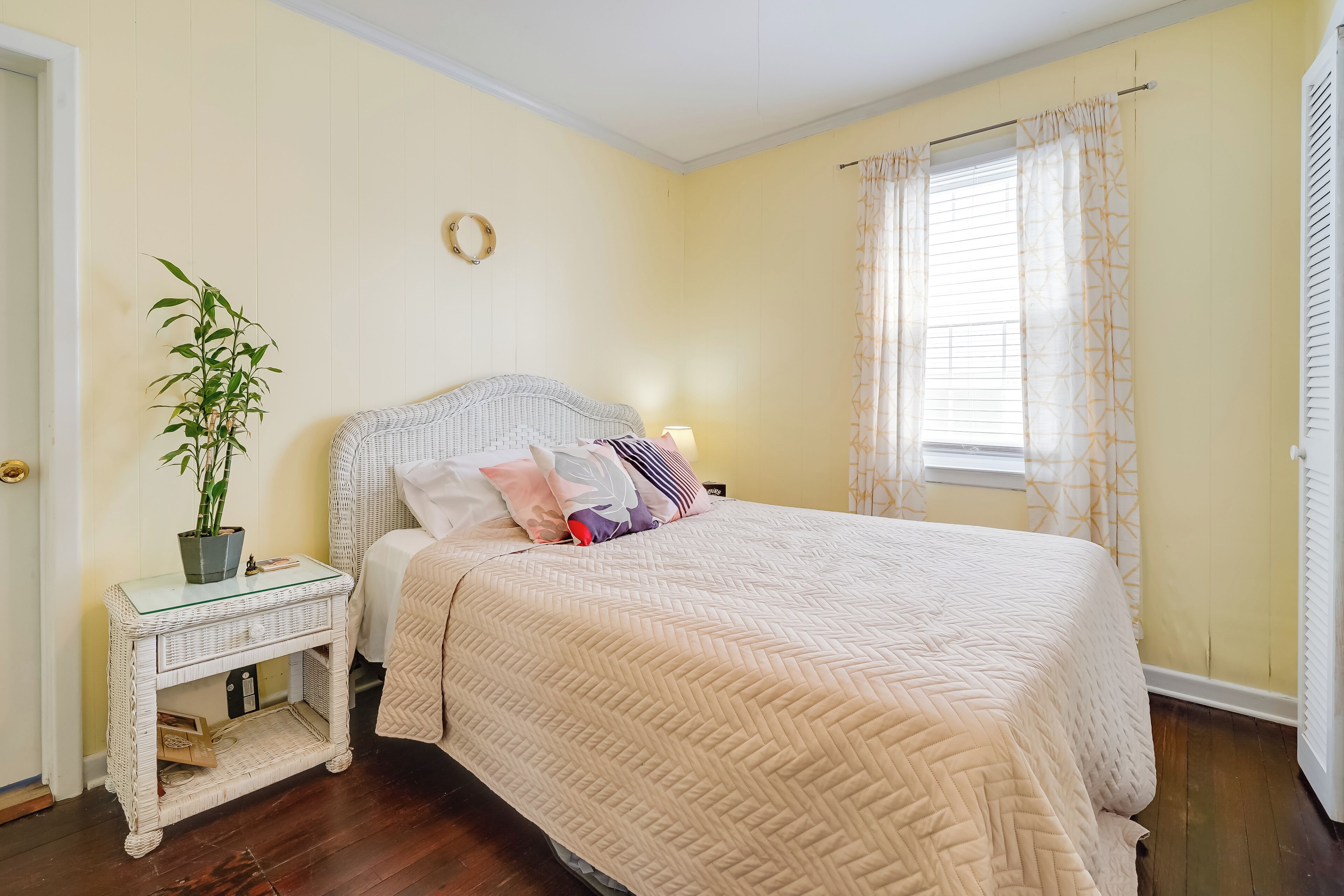 Un dormitorio con cama, mesita de noche, lámpara y una planta en maceta.
