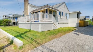 A two-story house with a porch, a chimney, and a gravel driveway. - Carolina Beach Home w/ Private Deck: Walk to Shore (Carolina Beach)