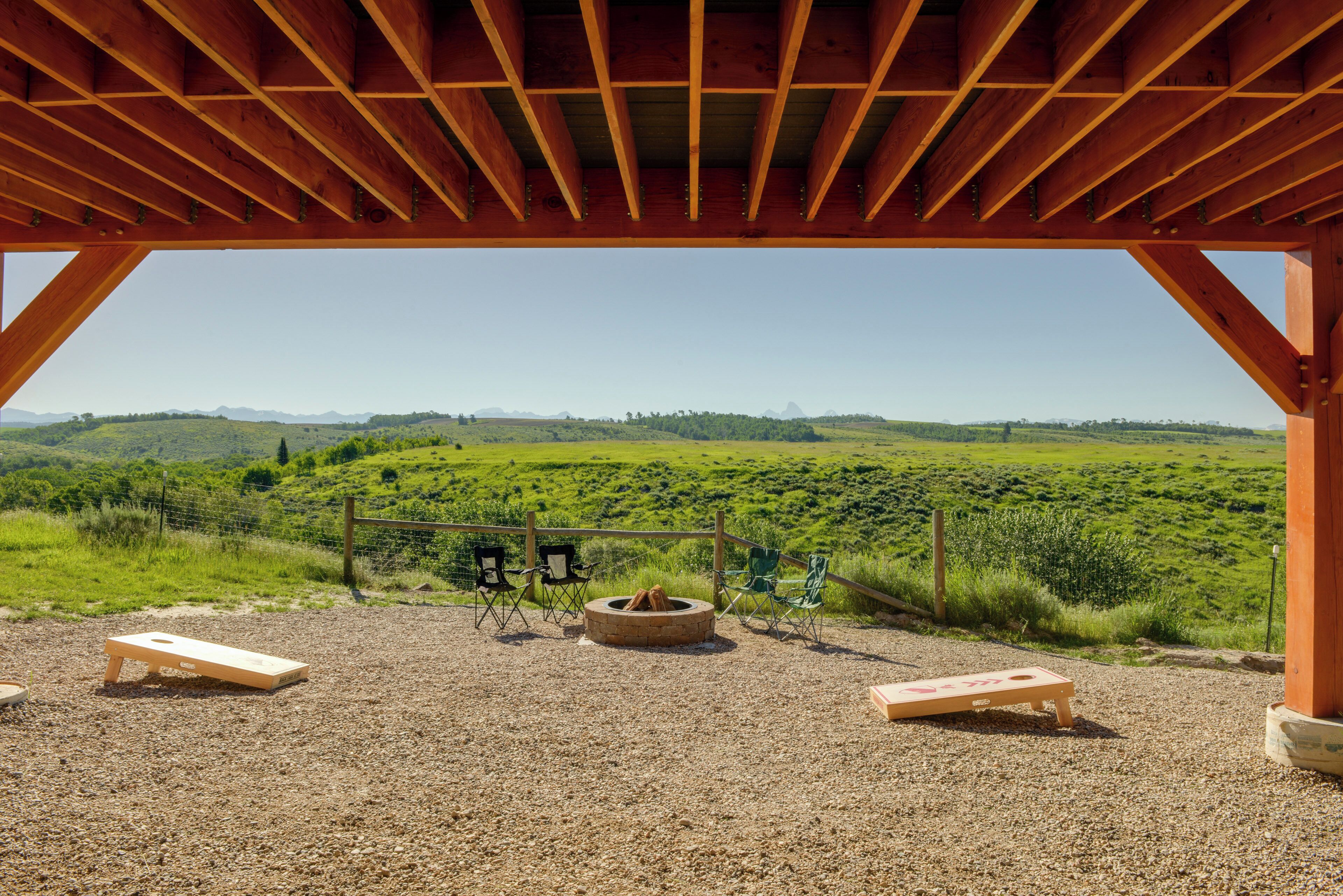 An outdoor seating area with a fire pit, two folding chairs, and a wooden bench.