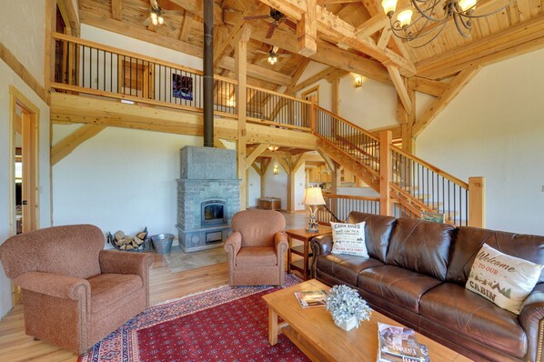 A spacious living room with a fireplace, wooden beams, a leather sofa, and a staircase.