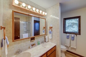 A bathroom with a large mirror, vanity with a sink, and a toilet.