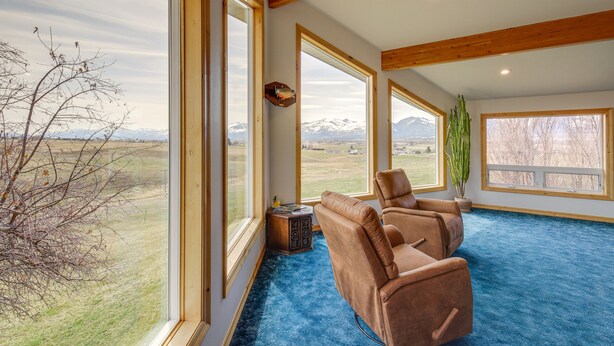 A spacious room with large windows offering a view of a mountainous landscape.