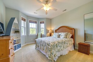 A bedroom with a bed, dresser, windows, and a ceiling fan. - Carolina Beach Lakefront House: Walk to Beach! (Carolina Beach)