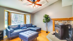 A modern living room with a sectional sofa, a fireplace, and a ceiling fan. - Lakefront New York Abode w/ Deck, Grill & Fire Pit (Mahopac)
