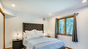 A bedroom with a large bed, nightstands, a window with curtains, and a wooden floor. - Lakefront New York Abode w/ Deck, Grill & Fire Pit (Mahopac)