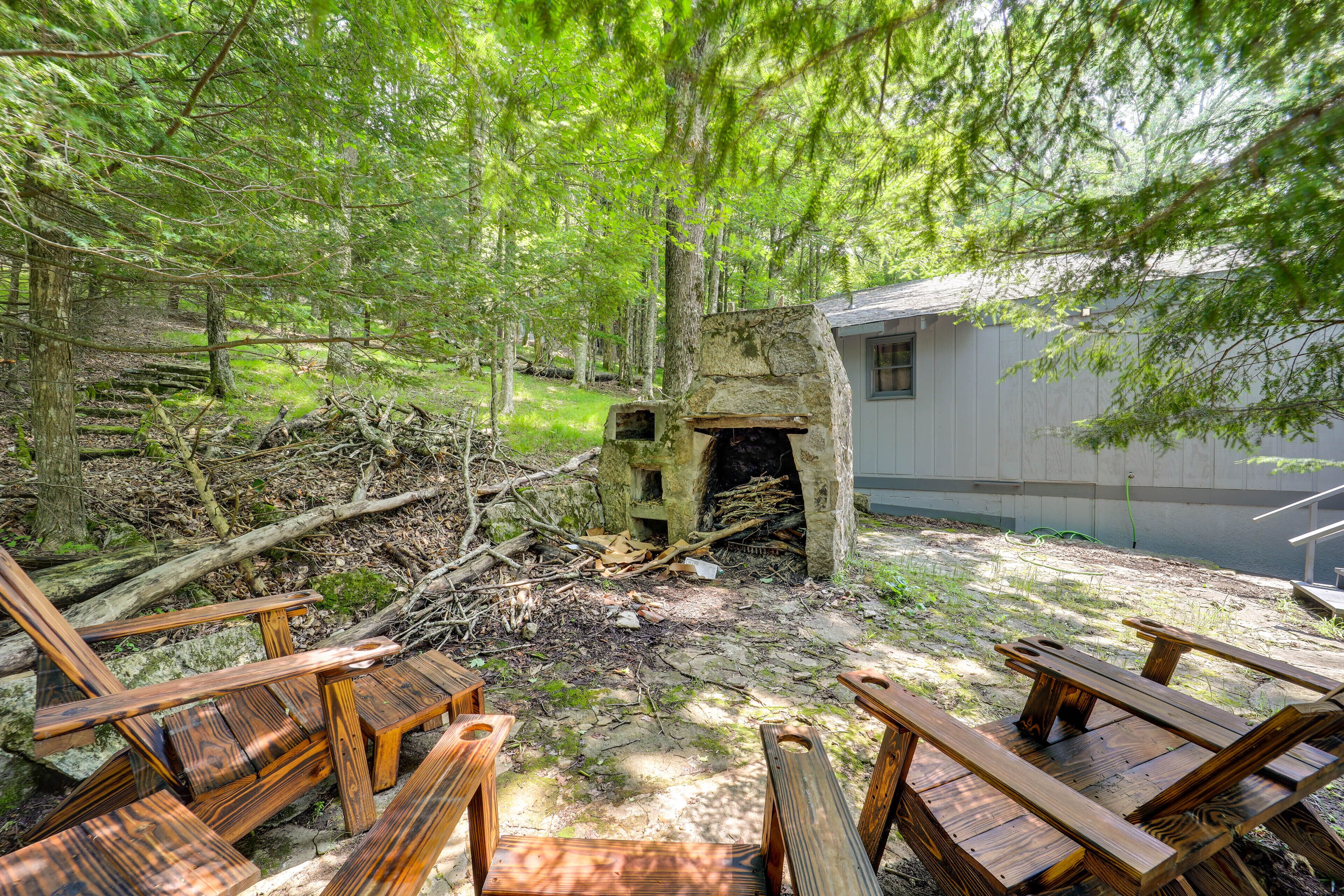A rustic outdoor seating area with wooden benches and a stone fireplace.