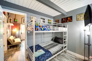 A bunk bed room with a desk and chair, a small couch, and a wall with framed pictures.