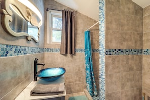 A bathroom with a blue ceramic basin, a towel rack, and a shower curtain.