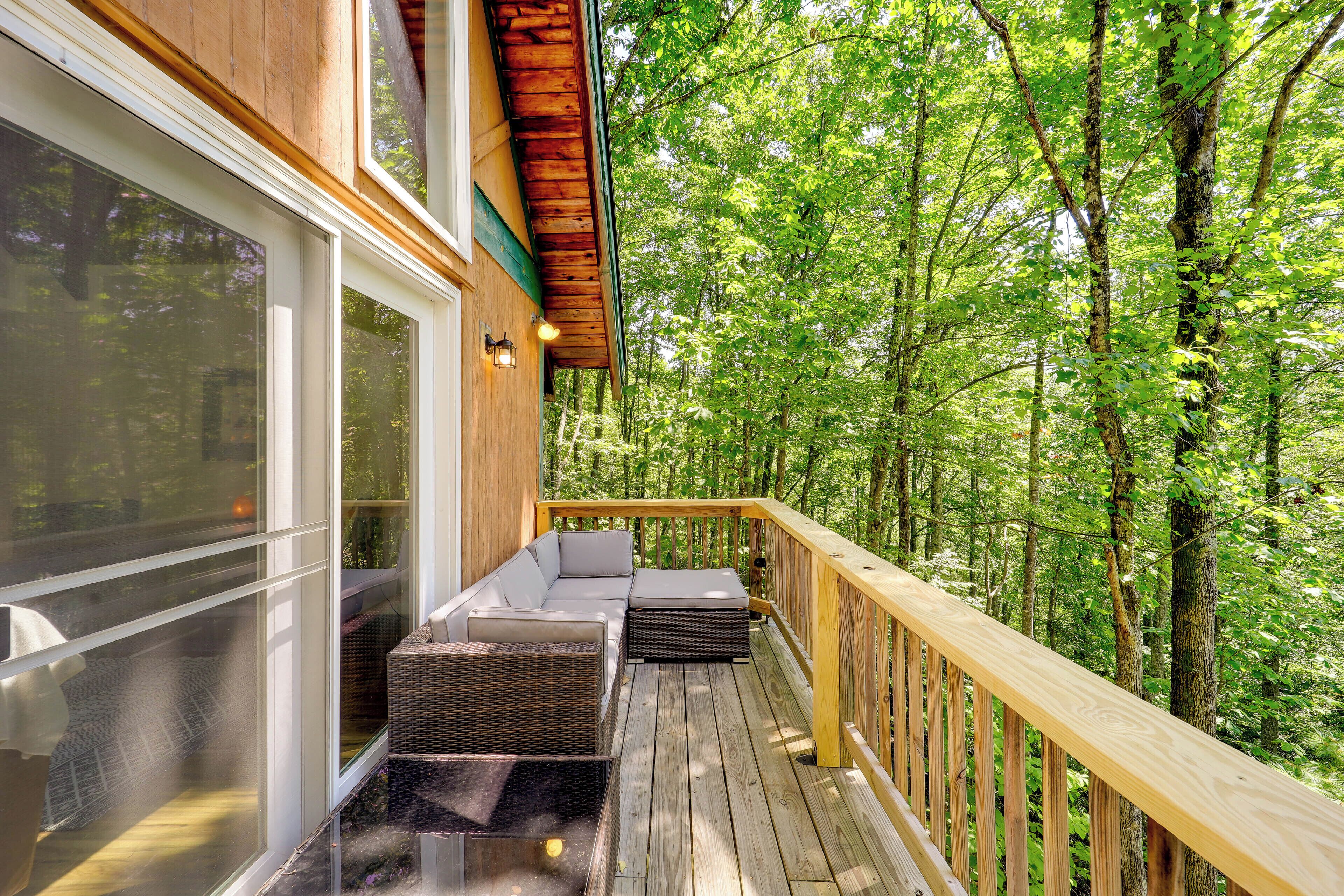 A wooden deck with a built-in sofa and a glass door leading to a room.