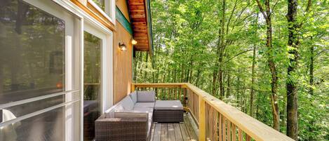 A wooden deck with a built-in sofa and a glass door leading to a room.