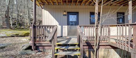 A wooden cabin with a porch, a staircase, and a door.