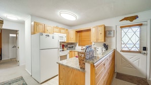 A compact kitchen with wooden cabinets, a refrigerator, microwave, and a coffee maker. - Ski, Hike & Explore! All-season Condo in Beech Mtn (Banner Elk)