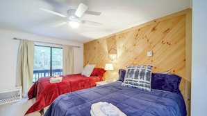 A bedroom with two beds, a ceiling fan, a window with curtains, and a wooden wall panel. - Ski, Hike & Explore! All-season Condo in Beech Mtn (Banner Elk)