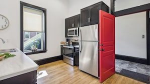 A modern kitchen with dark cabinets, a stainless steel refrigerator, a microwave, and an oven. - Sleek Millersburg Apartment in Downtown! (Millersburg)