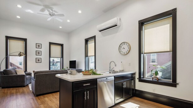 A modern kitchen with a central island, built-in appliances, and large windows. - Sleek Millersburg Apartment in Downtown! (Millersburg)