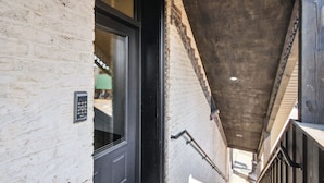 A narrow stairway with a white brick wall and a black door. - Sleek Millersburg Apartment in Downtown! (Millersburg)
