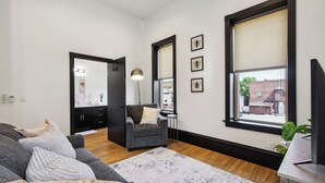 A modern living room with a grey sofa, a patterned rug, and a black-framed mirror. - Sleek Millersburg Apartment in Downtown! (Millersburg)