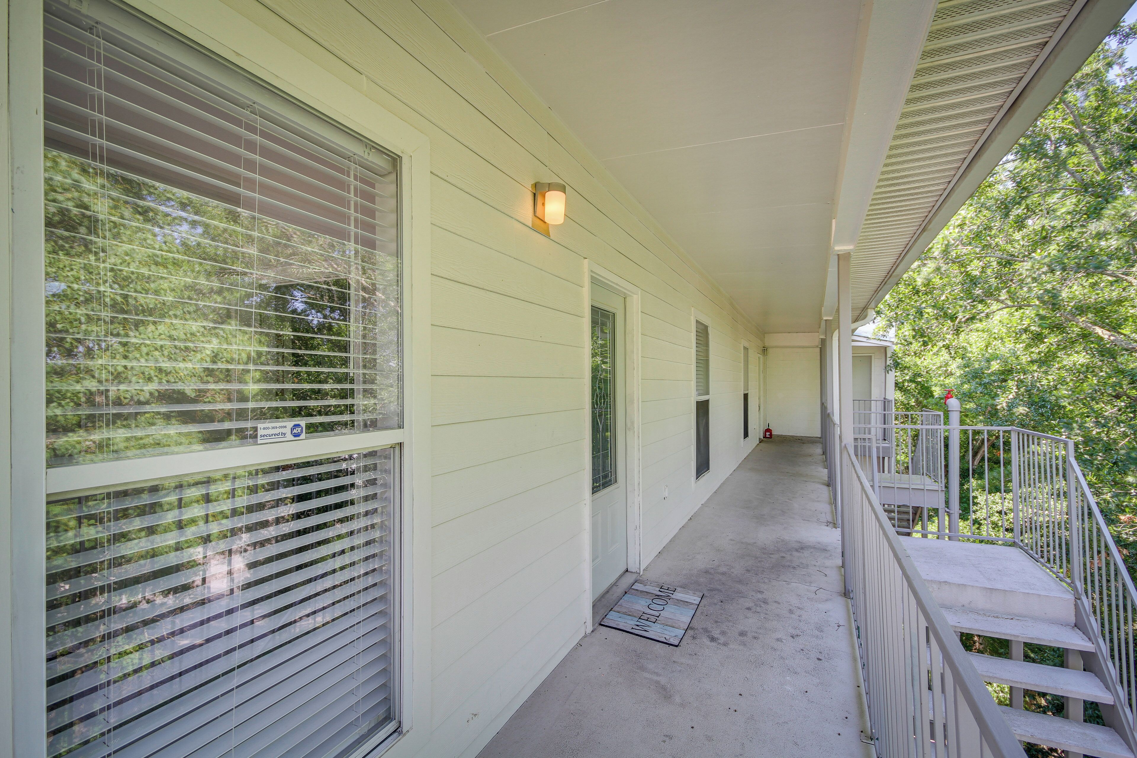 A covered porch with a metal railing, a welcome mat, and a light fixture.