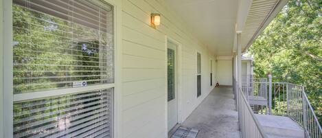 A covered porch with a metal railing, a welcome mat, and a light fixture.
